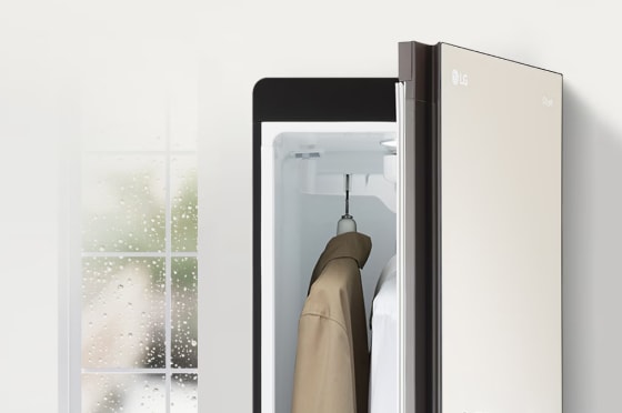 창밖으로 비가 오는 모습이 보여지고 그 옆에는 열려있는 스타일러와 내부 겉옷이 걸려있습니다.