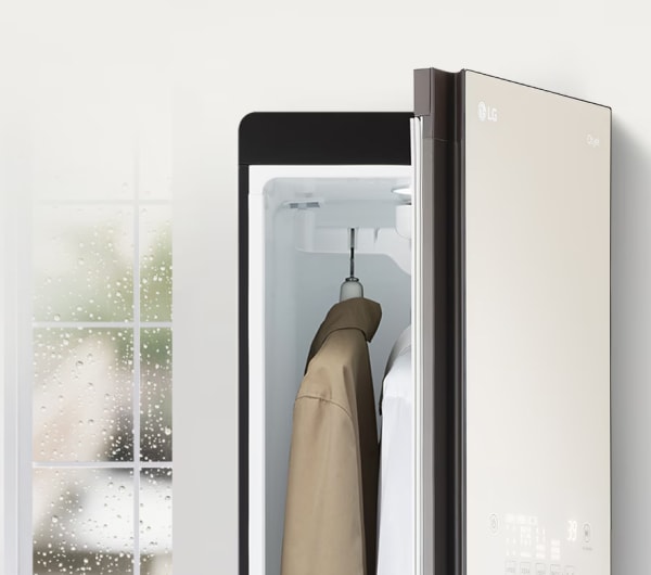 창밖으로 비가 오는 모습이 보여지고 그 옆에는 열려있는 스타일러와 내부 겉옷이 걸려있습니다.