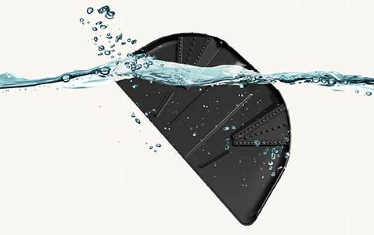 검은색 반원형 물체가 물속에 잠겨 있으며, 물방울이 물체 주변에 퍼져 있는 모습입니다. 물은 투명하고 물체의 일부를 덮고 있으며, 물체 표면에는 선형 패턴이 보입니다.