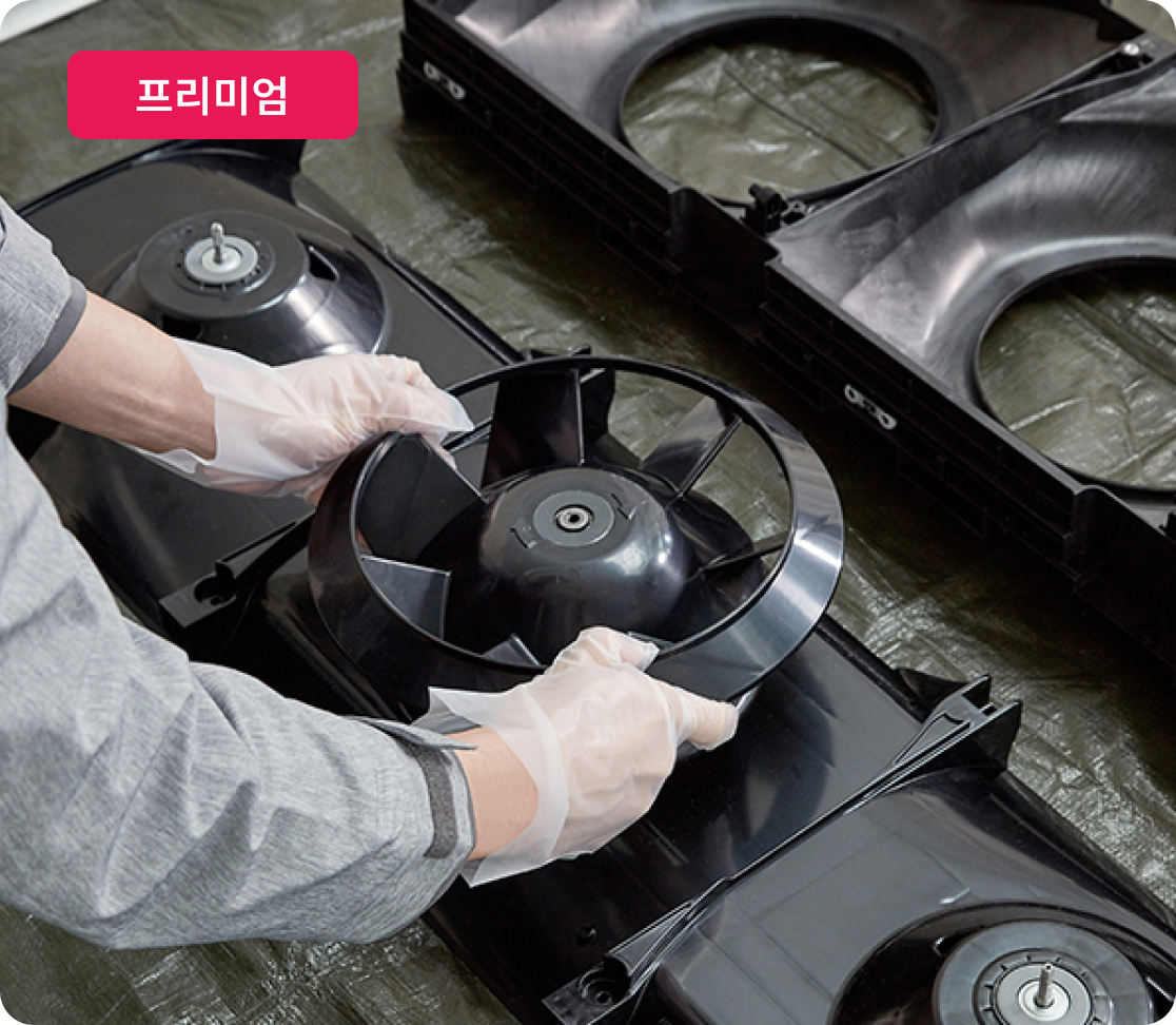 전문가가 위생 장갑을 끼고 LG 스탠드형 에어컨 내부 팬을 분해하여 세척 준비 중. 상단에 프리미엄 라벨 표시됨.