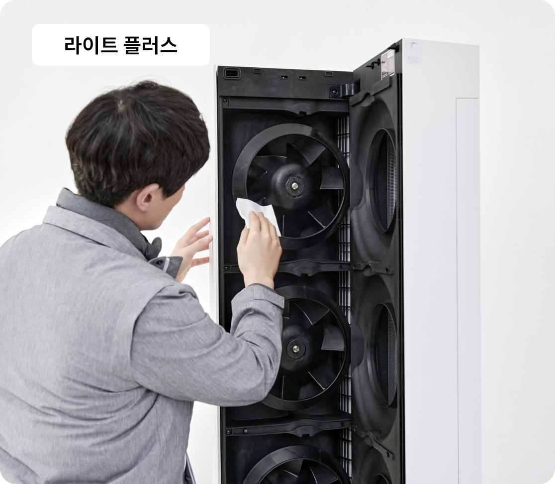 전문가가 LG 스탠드형 에어컨 내부 팬을 천으로 닦으며 청소 중. 상단에 라이트 플러스 라벨 표시됨.