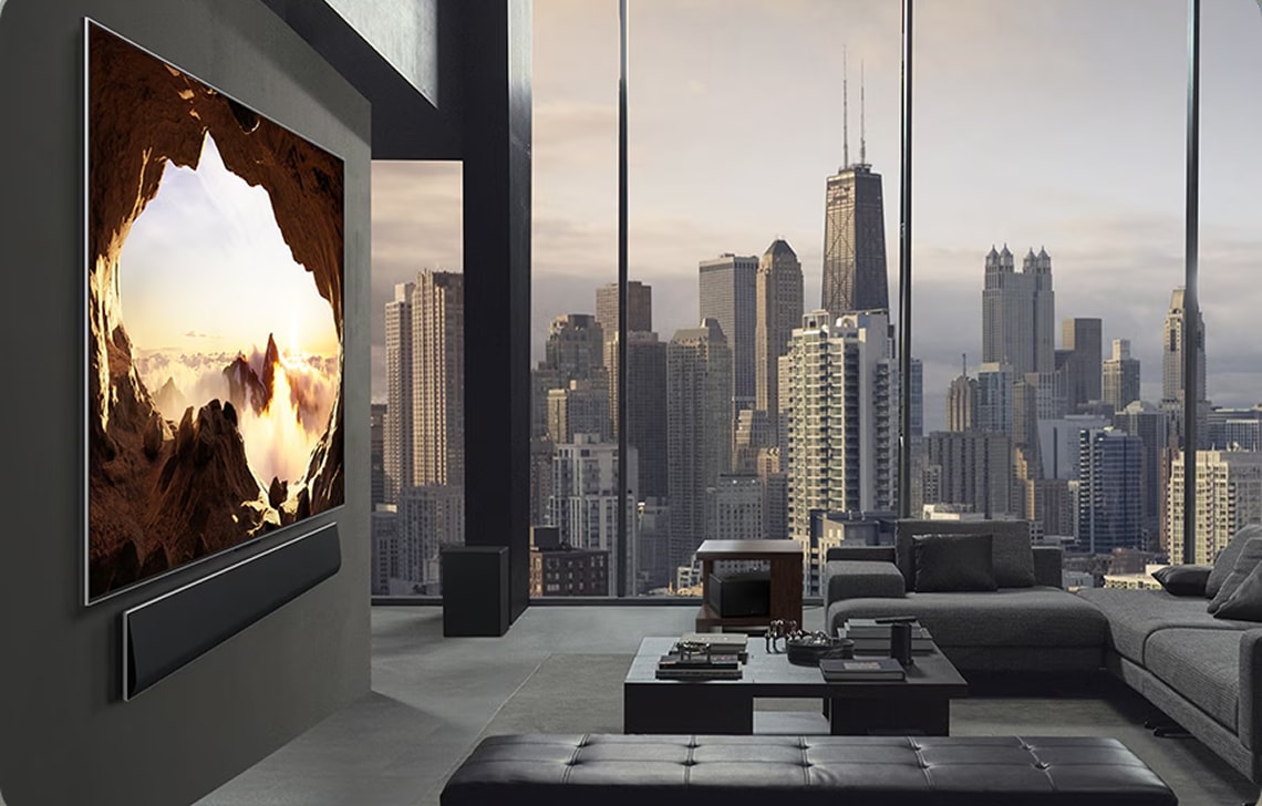 도심 전경이 보이는 고급 거실에 설치된 LG TV 화면에 자연 풍경이 선명하게 표현된 모습.