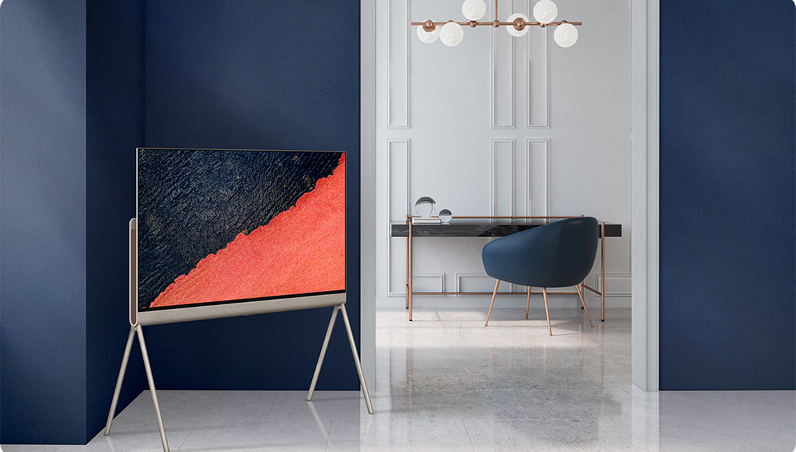 세련된 인테리어 공간에 스탠드형으로 배치된 LG TV, 화면에는 검은색과 붉은색이 대각선으로 나뉜 추상적인 이미지가 표현된 모습.