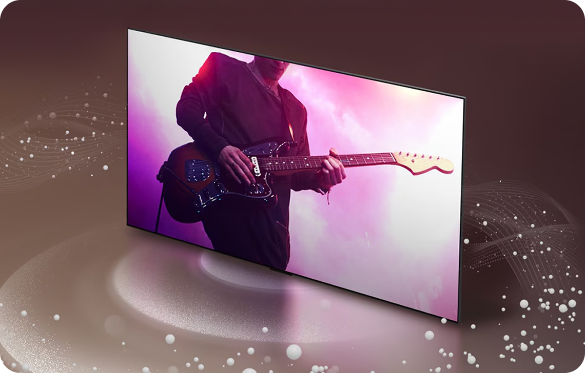 기타를 연주하는 공연 장면이 화면에 크게 나타난 슬림 TV가 어두운 배경 위에 놓여 있으며, TV 주변에는 사운드를 시각적으로 표현한 빛과 입자 효과가 퍼져 있다.