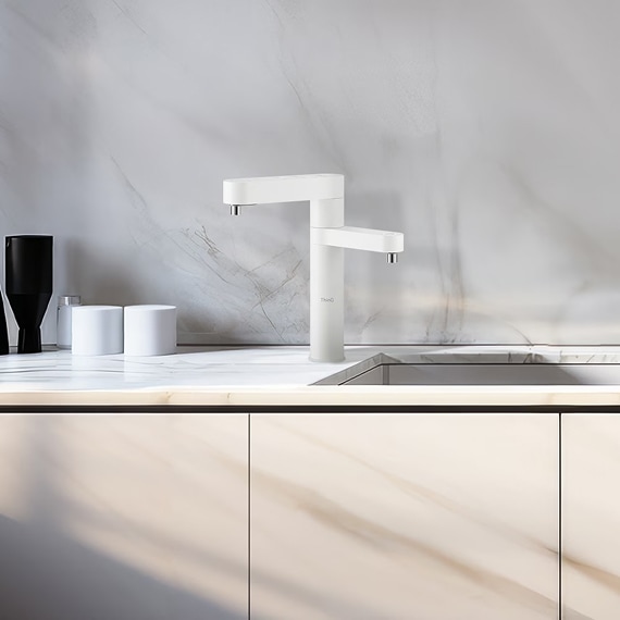 대리석 느낌으로 인테리어 된 주방. 검정색 양념통과 하얀 컵이 놓여있으며, 중간에 화이트 색상의 듀얼 정수기가 설치되어 있는 모습.