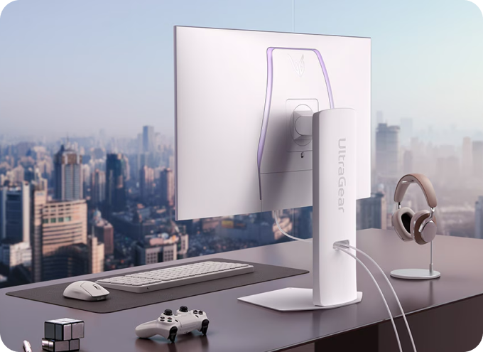 도시 전경이 보이는 창가에 놓인 책상 위에 LG UltraGear 모니터 뒷면이 보이는 모습.