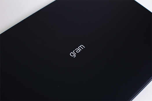 닫힌 검정색 LG 그램 노트북의 상판 중앙에 새겨진 'gram' 로고가 클로즈업된 모습