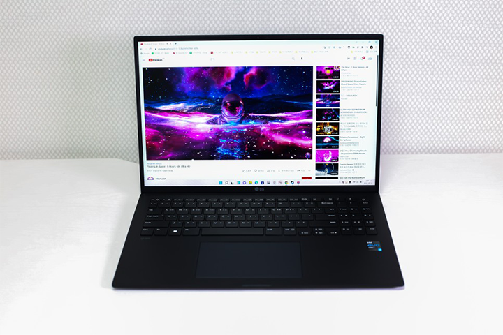 LG 그램 노트북이 열려 있는 정면 모습으로, 화면에는 유튜브 동영상이 재생되고 있고 검정색 키보드와 넓은 터치패드가 보임