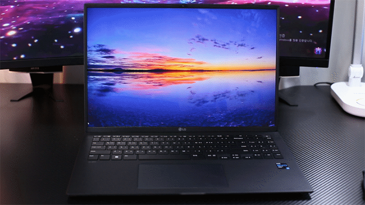 LG 그램 16Z95P 노트북이 책상 위에 놓여 있으며, 화면에는 고화질의 노을 지는 바다 풍경이 생생하게 표시된 모습