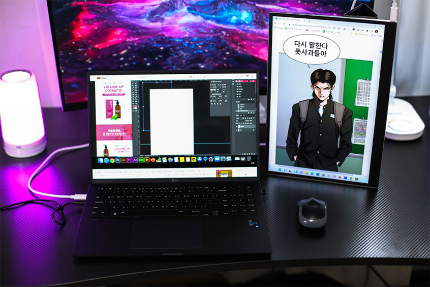 책상 위에 놓인 LG 노트북과 세로로 배치된 그램+view 포터블 듀얼 모니터. 노트북 화면에는 그래픽 작업 프로그램이 실행 중이고, 포터블 모니터에는 웹툰 장면이 크게 표시되어 있음