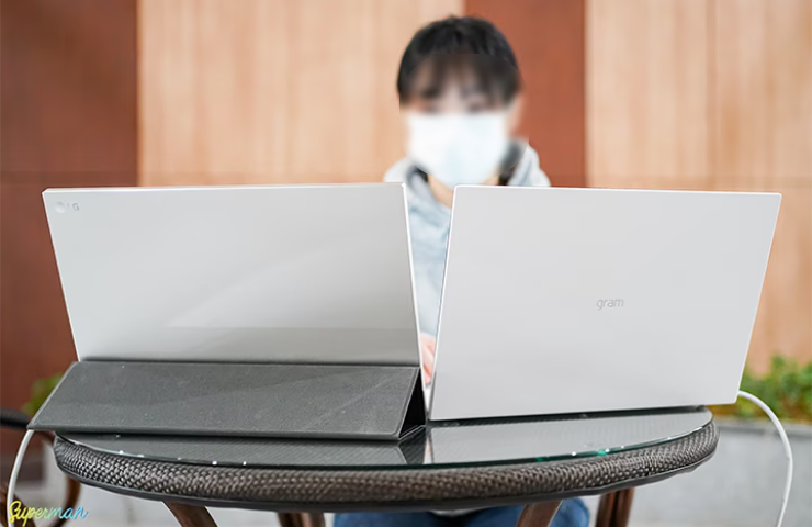 카페 테이블 위에 LG 그램 노트북과 포터블 듀얼 모니터 ‘그램+view’를 나란히 배치한 모습으로, 사용자가 두 화면을 활용하여 작업하는 장면.