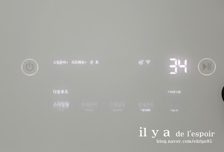 LG 스타일러의 디스플레이 화면이 켜져 있는 모습으로, 다운로드된 스타일링 코스가 표시되어 있고 남은 시간이 34분으로 나타나 있다.