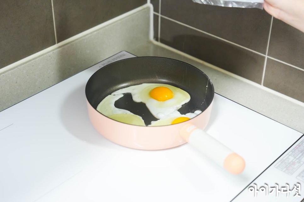 lg_디오스_오브제컬렉션_인덕션_위에_올려진_분홍색_프라이팬에서_계란_프라이_두_개가_익어가는_모습._계란의_노른자가_선명하게_보인다.
