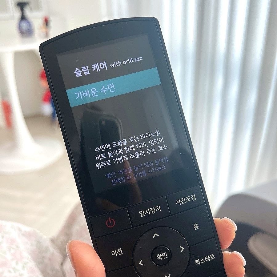 손에_들린_lg_힐링미_mx9_안마의자_리모컨의_화면이_확대되어_있고,_화면에는_슬립케어_코스의_가벼운_수면이_선택되어_있다._