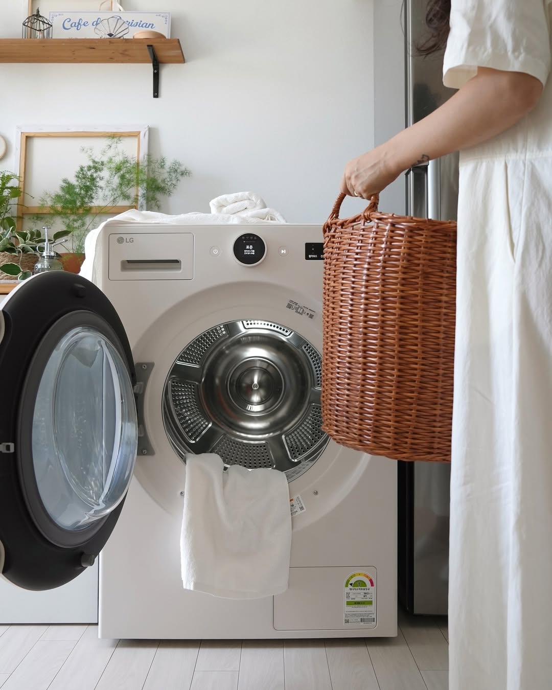 LG 트롬 오브제컬렉션 건조기의 문이 열려 있고, 사용자가 세탁 바구니를 들고 건조기에 빨래를 넣는 장면.