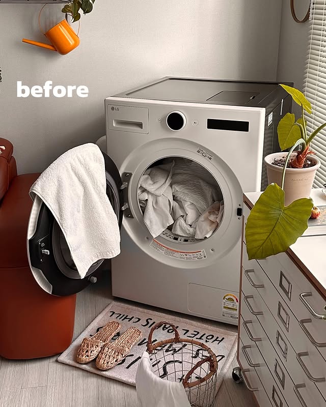 'before'라는 글자가 표시된 상태에서 문이 열린 LG 트롬 오브제컬렉션 건조기. 내부에는 세탁물이 가득하며, 주변에는 빨래 바구니와 수건이 놓여 있는 일상적인 모습.