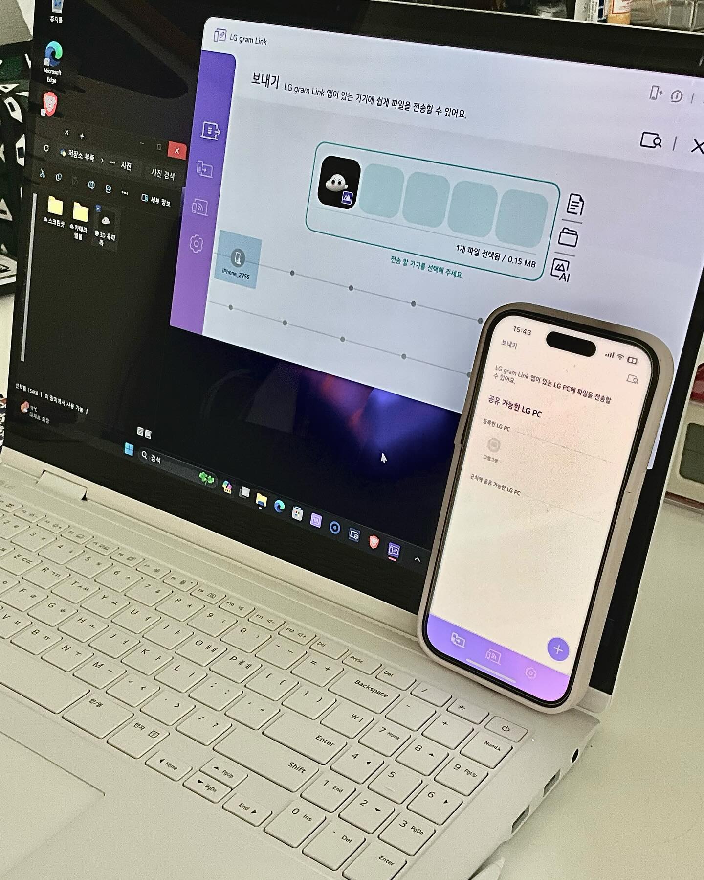 LG 그램 노트북과 스마트폰이 LG Gram Link 앱으로 파일 전송 중인 화면. 노트북 화면에 전송 상태가 표시되고, 스마트폰에는 연결된 장치 정보가 나타남.