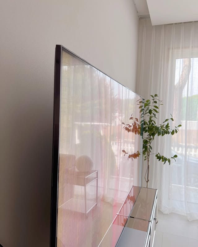 측면에서 본 LG QNED evo TV의 얇은 디자인과 반사되는 거실 내부 모습.