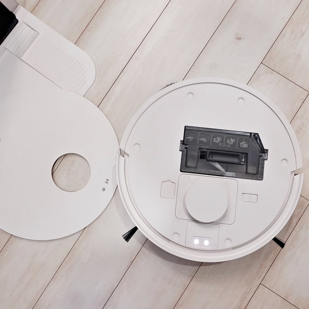 LG 코드제로 로보킹 AI 올인원의 상단 덮개가 열린 모습. 내부에는 먼지통이 장착되어 있으며, 먼지통에는 청소 및 유지보수 방법이 그림 아이콘으로 표시되어 있다. 청소 후 먼지통을 쉽게 분리하여 관리할 수 있는 기능이 강조된 장면.