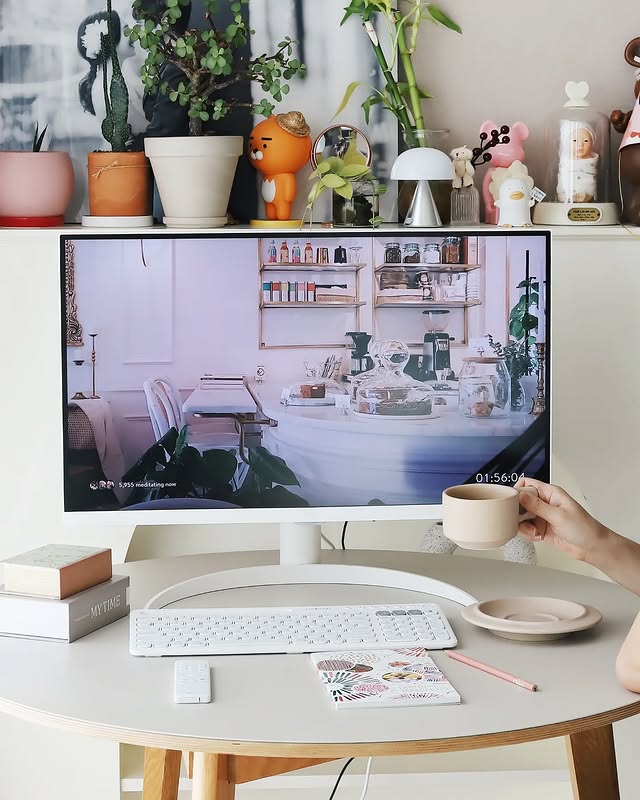 사용자가 책상에 앉아 LG 스마트 모니터를 보며 차를 마시는 모습이 담겼다. 모니터 화면에는 감성적인 인테리어 이미지가 표시되어 있으며, 책상 위에는 노트, 연필, 리모컨 등이 놓여 있어 편안한 공간 연출을 보여준다.