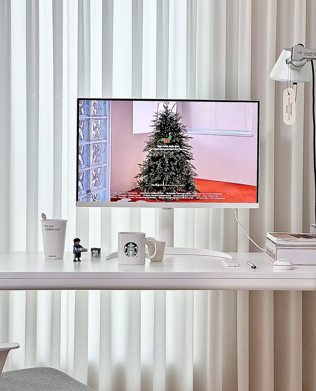 LG 스마트 모니터로 크리스마스 분위기의 콘텐츠를 감상하는 모습. 책상 위에는 따뜻한 음료와 소품들이 놓여 있으며, 모니터가 홈 엔터테인먼트용으로도 적합함을 보여준다.