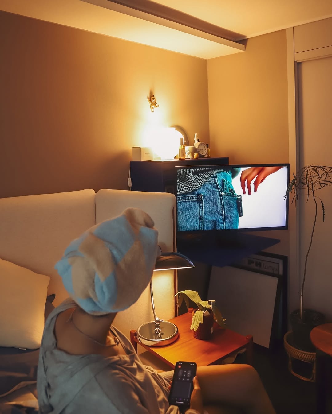 어두운 침실에서 침대에 누운 채 LG 스마트 모니터로 영상을 감상하는 모습. 은은한 조명과 블루 톤 침구가 조화롭게 연출된 공간.