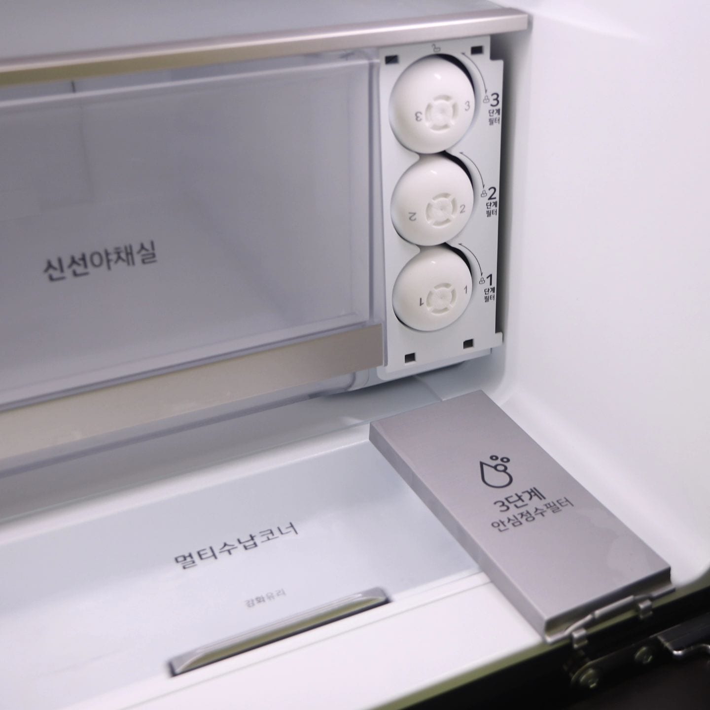 얼음정수 냉장고 내부의 신선 야채실 옆에 위치한 3단계 안심 청정 필터와 멀티 수납 코너로, 식품 보관과 위생 기능을 강조한 모습.