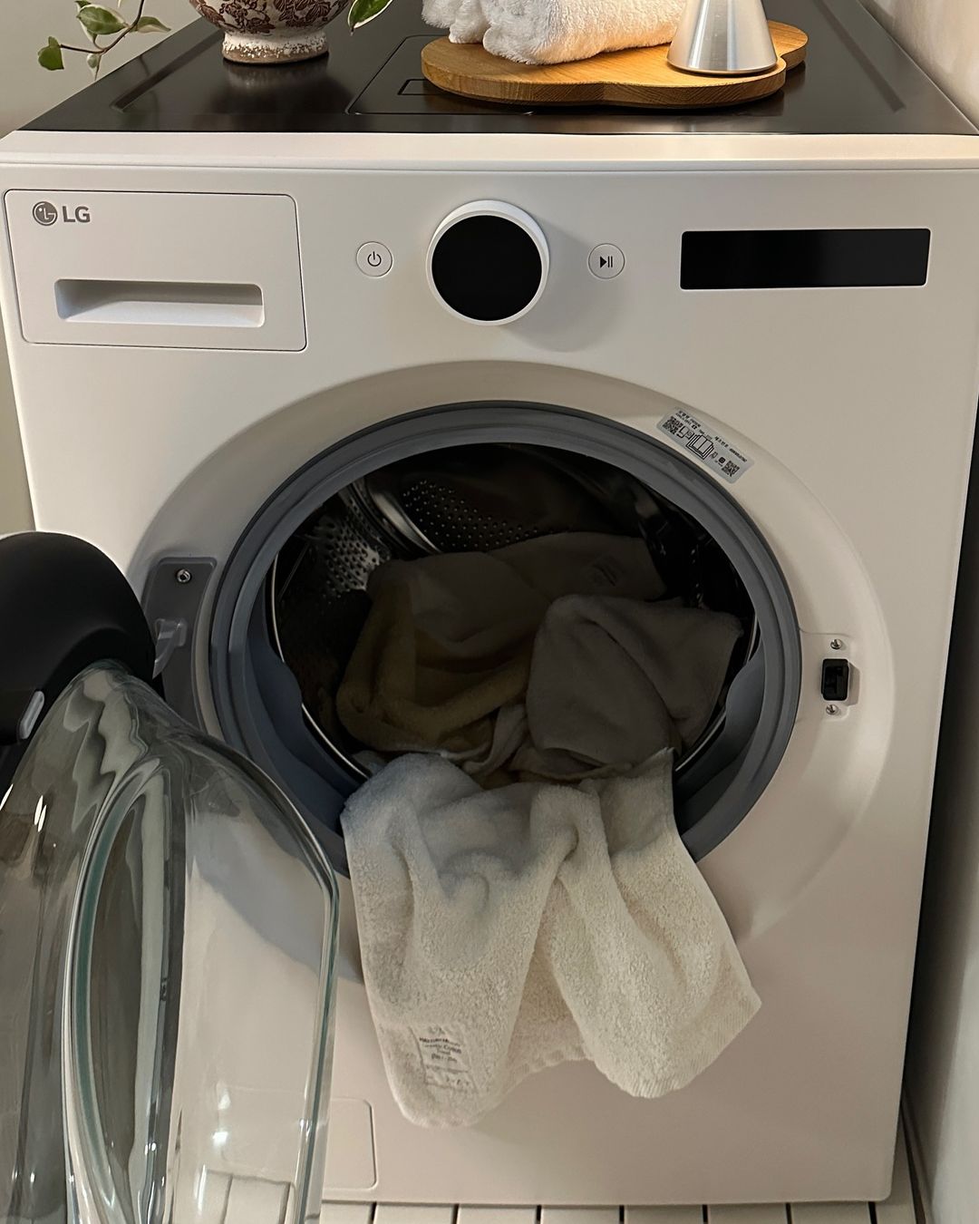 워시콤보 내부에 타월과 옷이 들어 있는 상태, 세탁 문이 반쯤 열려 있음.