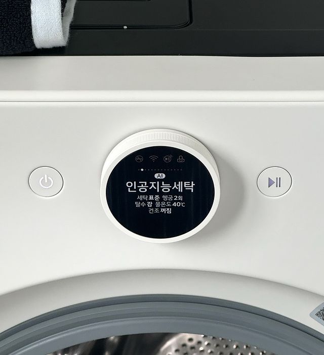워시콤보의 디스플레이에는 설정(인공지능세탁, 세탁표준 헹굼 2회, 탈수 강, 물온도 40도, 건조 꺼짐) 정보가 표시. 좌우로 전원, 일시정지 버튼이 보임.