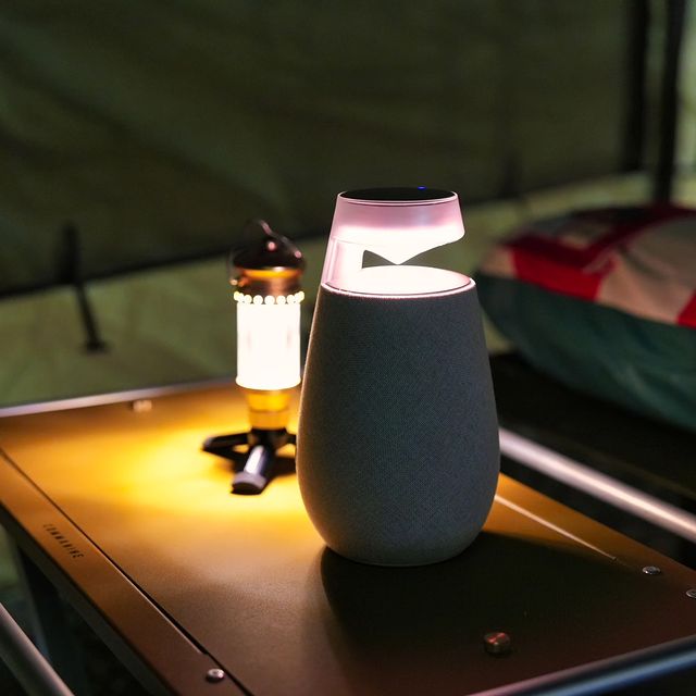 텐트 안, 캠핑 테이블 위에 놓인 점등된 엑스붐 360와 캠핑용 랜턴.