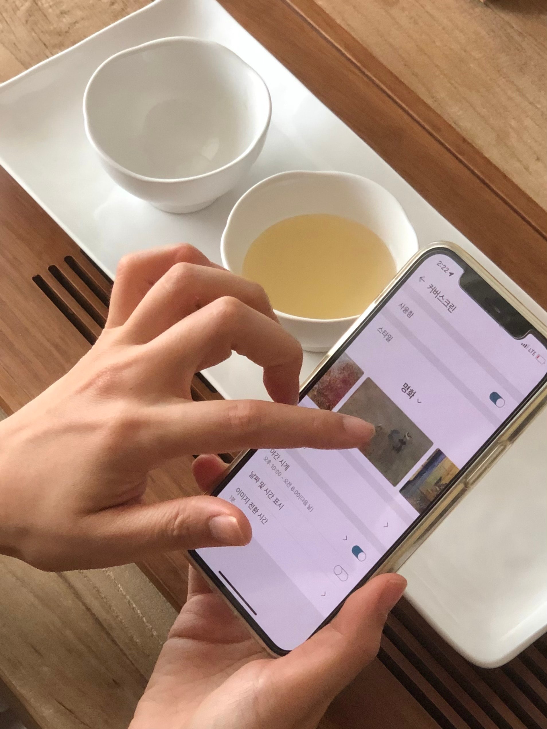 스마트폰 화면에 LG 휘센 오브제컬렉션 아트쿨의 커버스크린 설정 메뉴가 표시된 모습으로, 사용자가 이미지를 선택하며 화면을 조작하고 있음.
