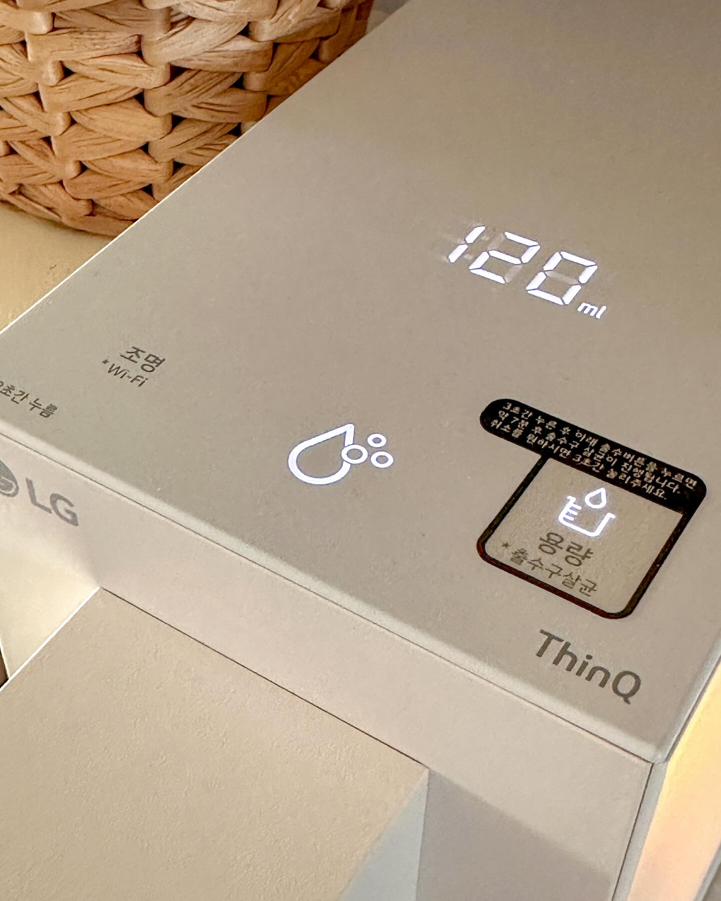 LG 정수기의 디지털 디스플레이가 120ml의 물을 설정하여 보여주고 있으며, 조명 및 Wi-Fi 기능이 활성화된 상태