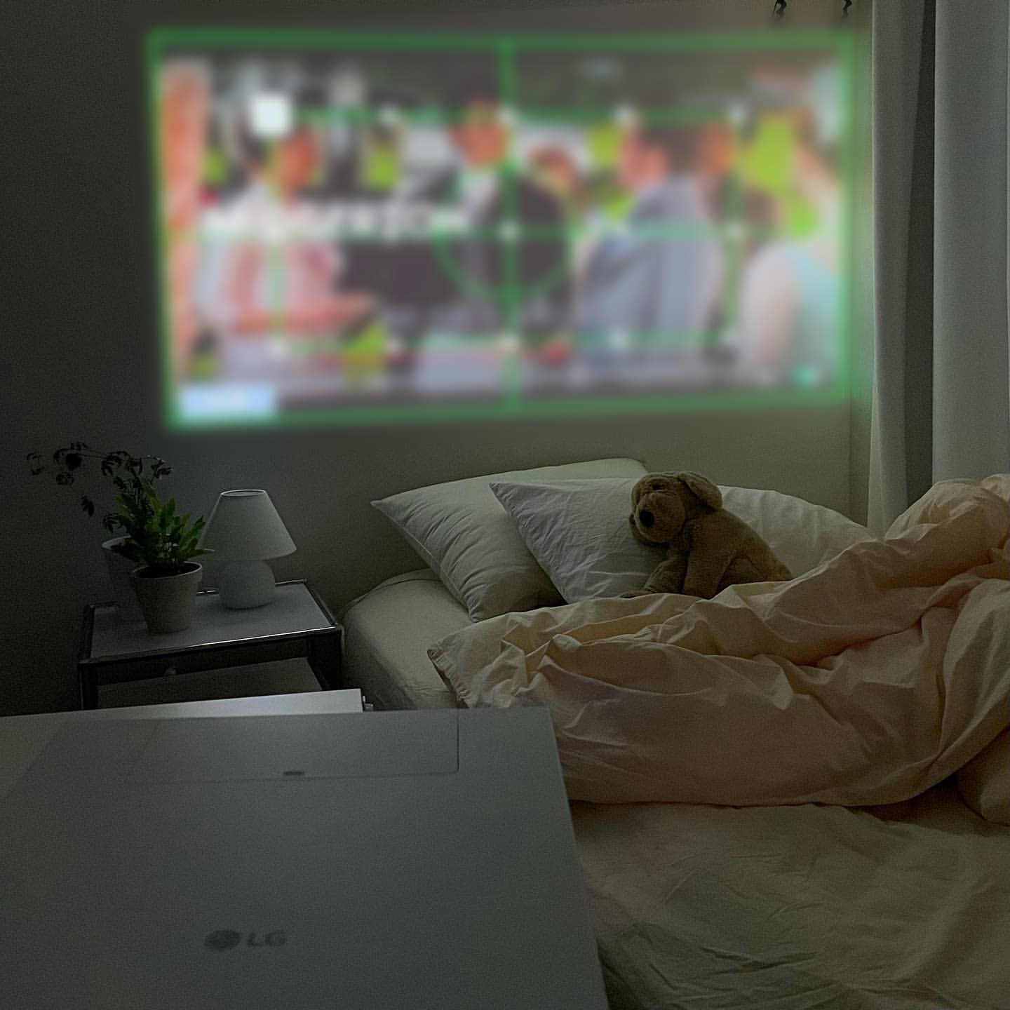 LG 시네빔이 설치되어 침대에 놓인 인형 옆 화면에 콘텐츠가 투사된 모습.