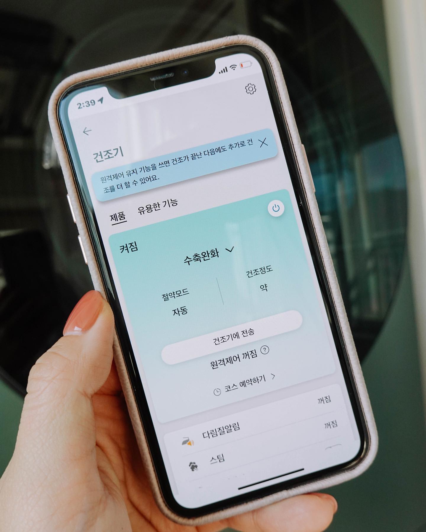 스마트폰 화면에 LG 건조기의 원격 제어 및 수축완화 코스가 선택된 상태가 표시된 모습.