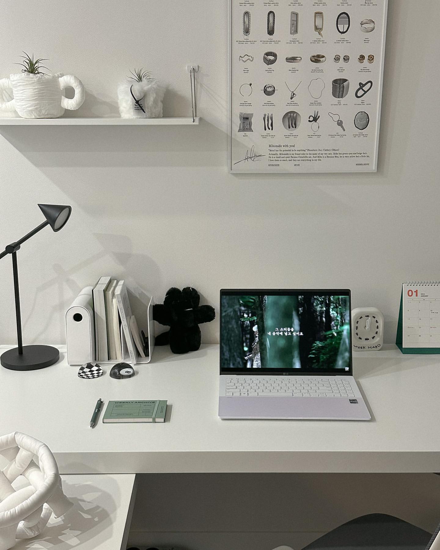 흰색 책상 위에 LG 그램 Style 노트북과 필기구, 작은 시계, 달력이 놓여 있으며 노트북 화면에는 숲속 나무 이미지가 표시된 모습.
