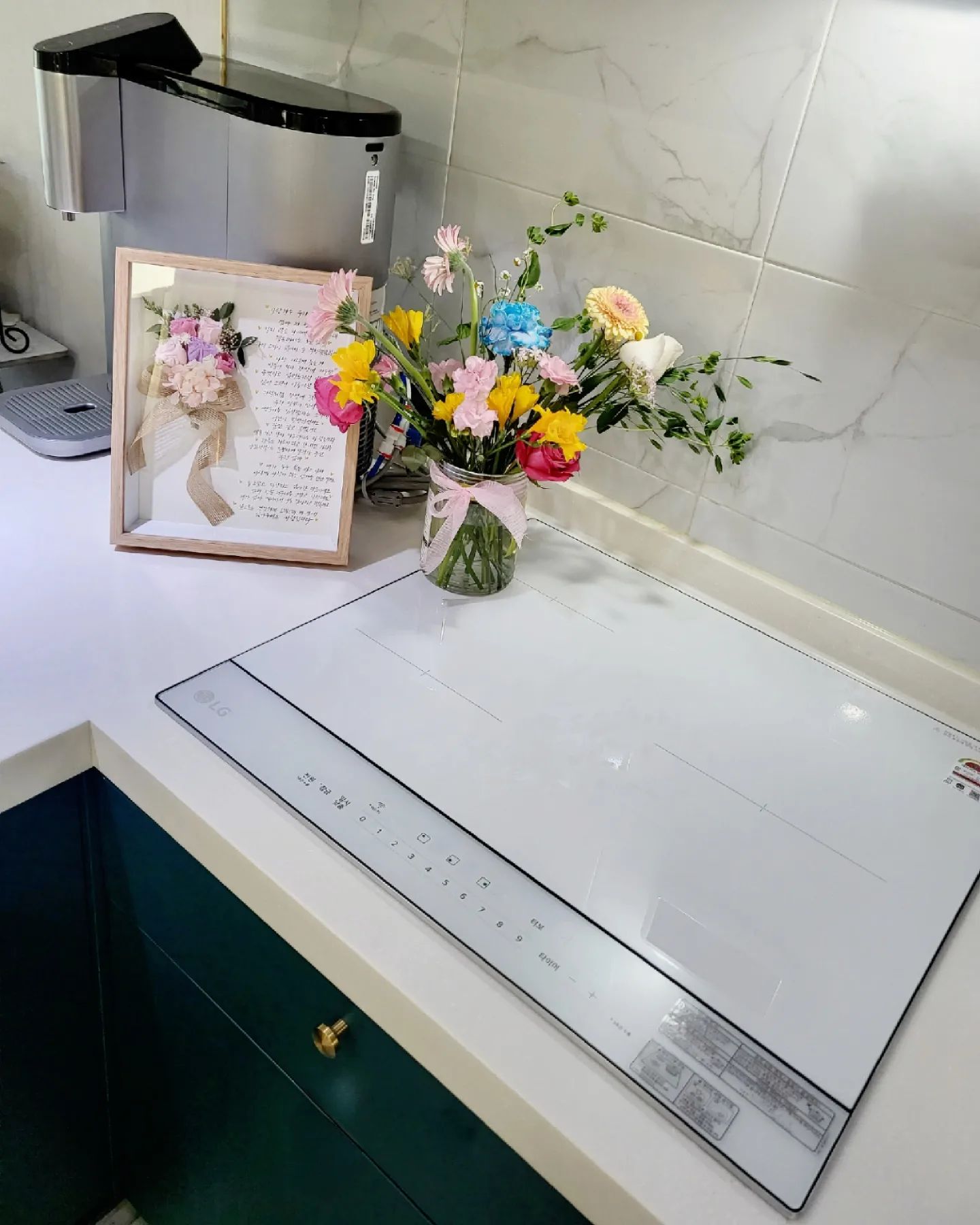 인덕션 옆 꽃이 담긴 병과 액자에 담긴 편지 