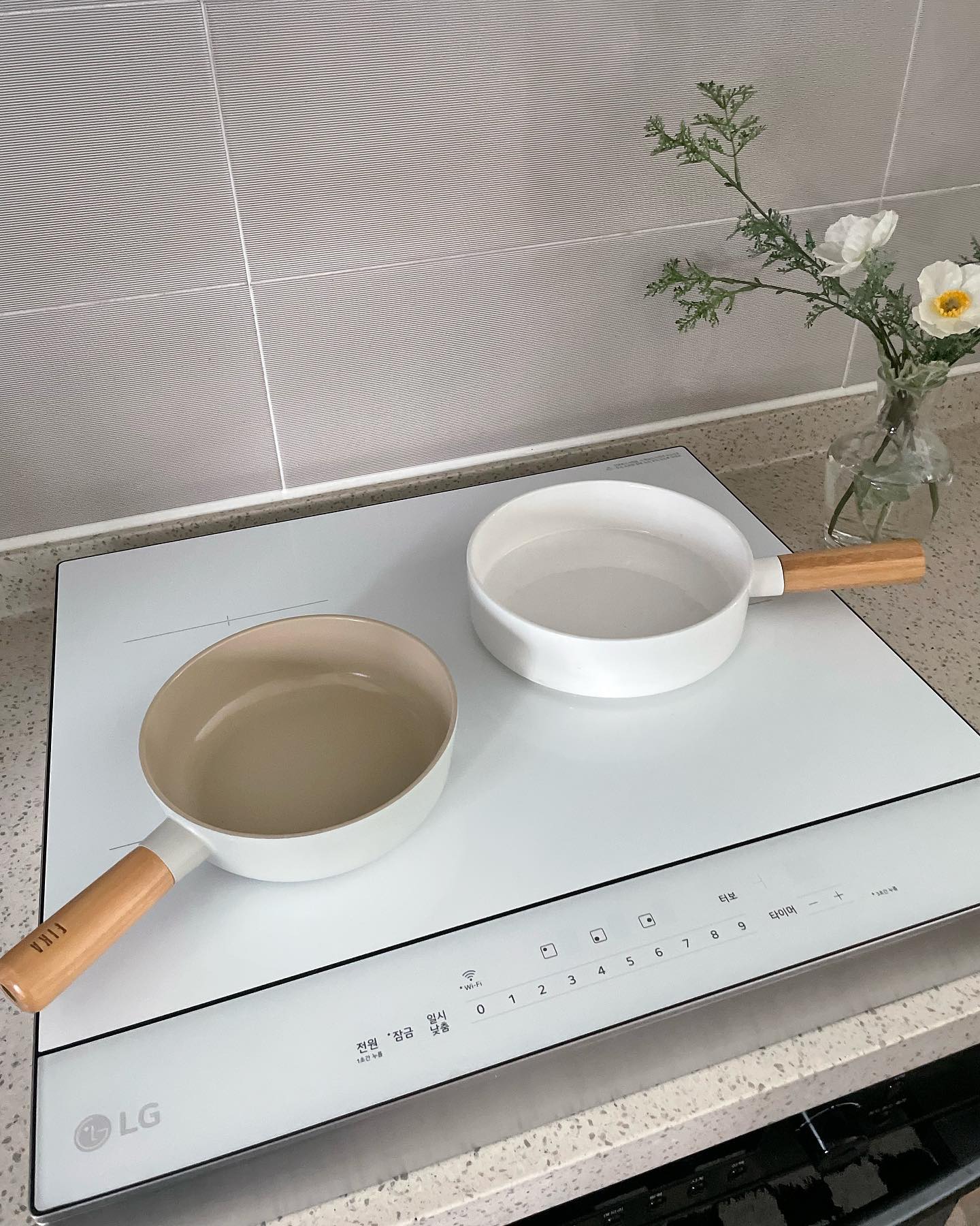 인덕션 위에 나무 손잡이 냄비 두 개가 비어 있는 상태로 놓여 있는 모습.