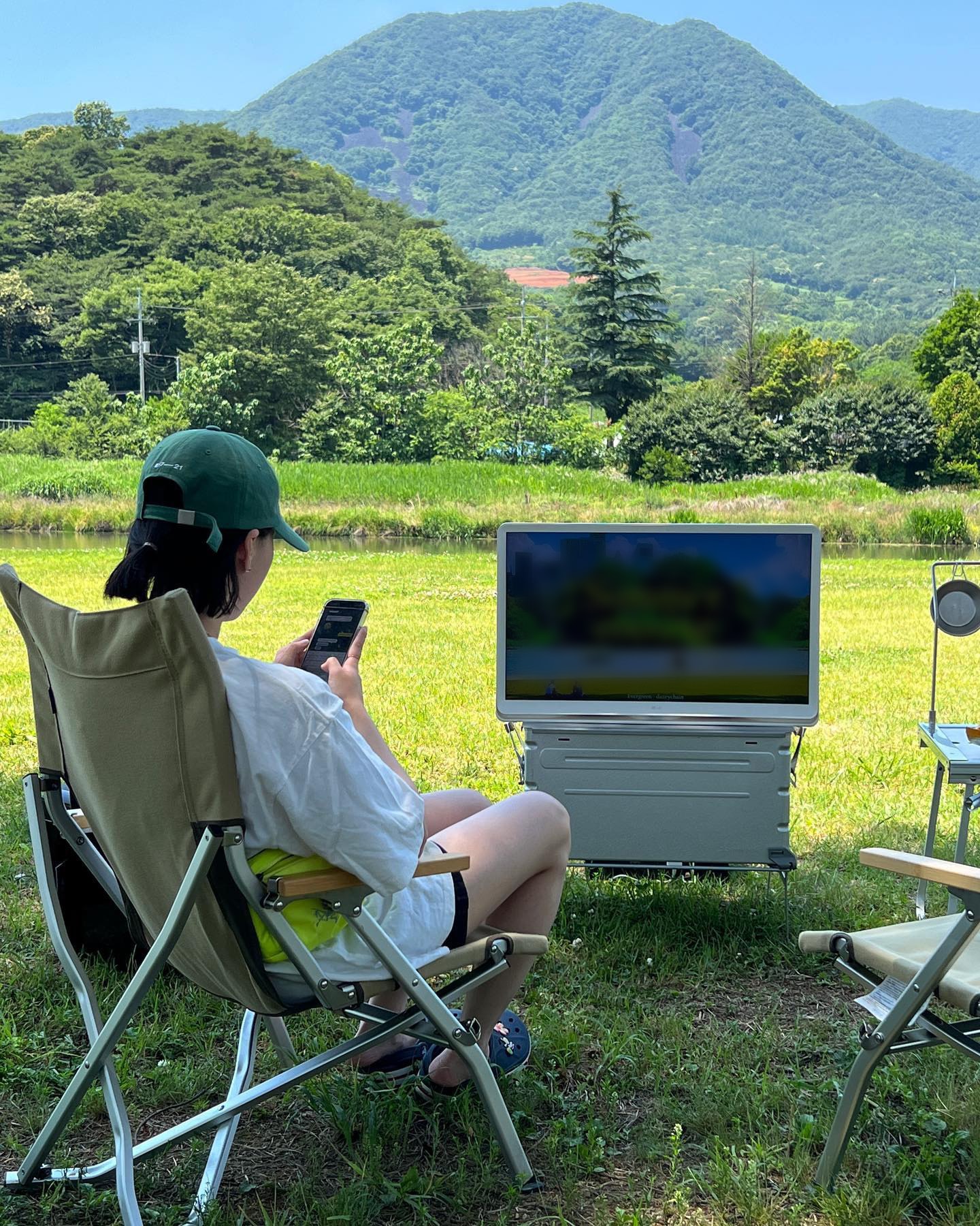 한 사람이 의자에 앉아 스마트폰을 사용하며 디스플레이를 바라보는 모습.