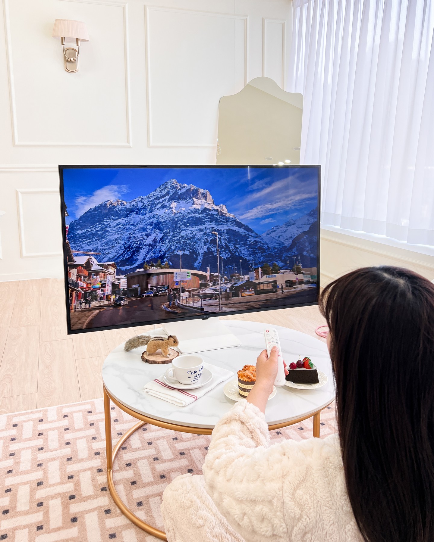 대리석 테이블 위에 디저트와 함께 TV 화면을 시청하는 모습.