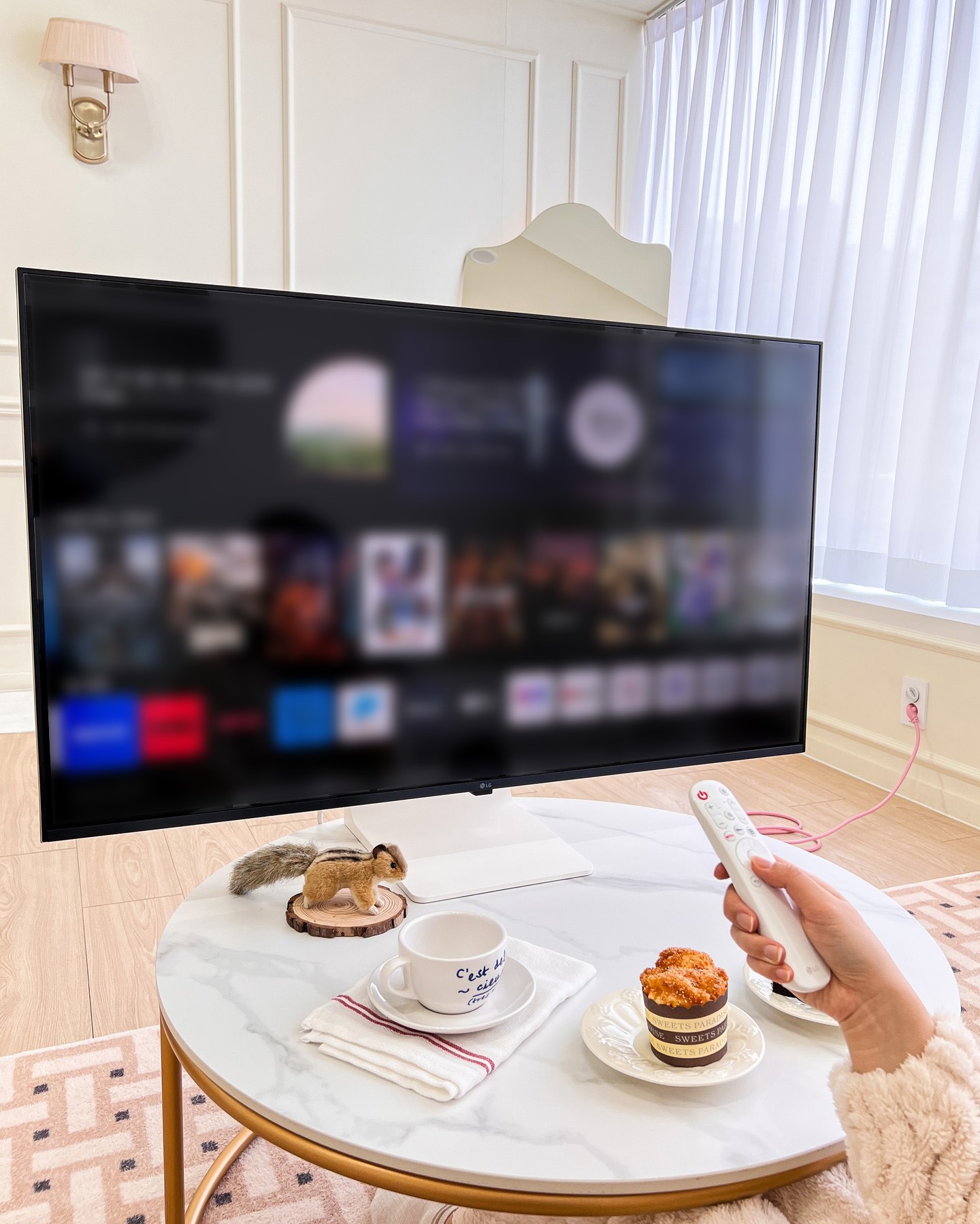대리석 테이블 위에서 리모컨으로 TV 화면을 조작하는 장면.