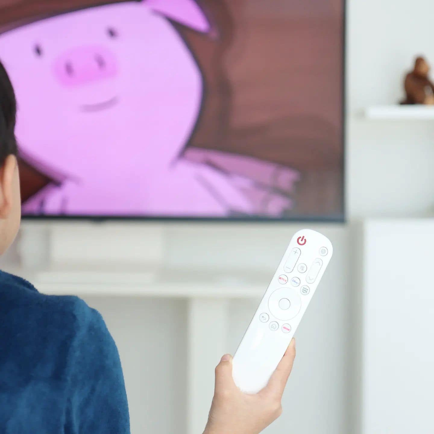LG 스마트 모니터 앞에서 아이가 리모컨을 들고 있는 모습이며, 화면에서는 애니메이션 돼지 캐릭터가 나오는 모습.