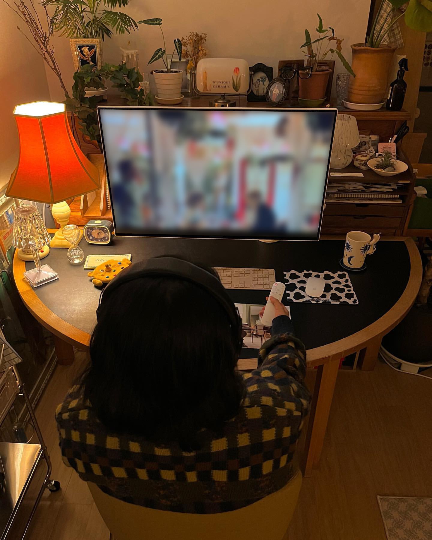 헤드폰을 낀 여성이 의자에 앉아 LG 스마트 모니터 리모컨을 작동 중인 모습.