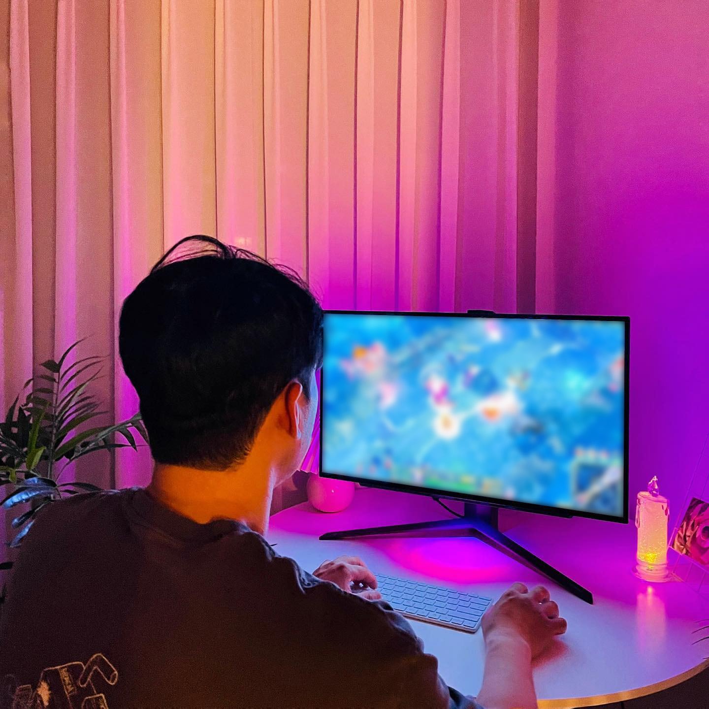 어두운 방에서 조명을 받은 모니터를 바라보는 사람의 뒷모습.