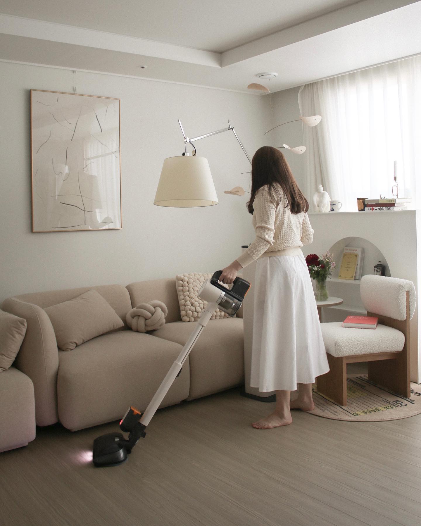소파 옆에서 바닥을 청소 중인 LG 무선 스팀 청소기 사용 장면.