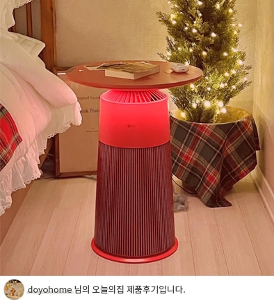 빨간색 LG 퓨리케어 오브제컬렉션 에어로퍼니처 상단에 책과 리모컨이 놓여 있는 모습과 하단에 'doyohome 님의 오늘의집 제품후기입니다.' 텍스트가 포함된 모습.