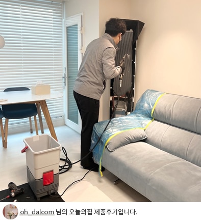 전문 기술자가 LG 휘센 오브제컬렉션 에어컨을 점검하고 청소하는 모습. 바닥에는 작업 도구와 보호 매트가 배치되어 있으며, 'oh_dalcom 님의 오늘의집 제품후기입니다.' 텍스트가 포함된 이미지.