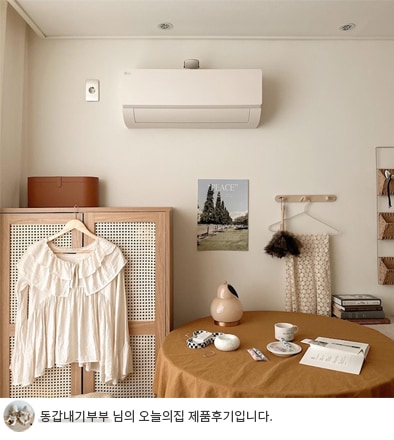 따뜻한 톤의 인테리어와 함께 LG 휘센 오브제컬렉션 사계절에어컨이 거실에 설치된 모습이며, '동갑내기부부 님의 오늘의집 제품후기입니다.' 텍스트가 포함된 이미지.