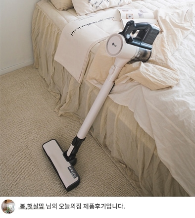LG 코드제로 오브제컬렉션 A9S 청소기가 베이지색 침대 옆에 놓여 있으며, 깔끔하게 정돈된 침구와 함께 편안하고 따뜻한 분위기를 연출. 하단 텍스트 포함: '봄,햇살맘 님의 오늘의집 제품후기입니다.'