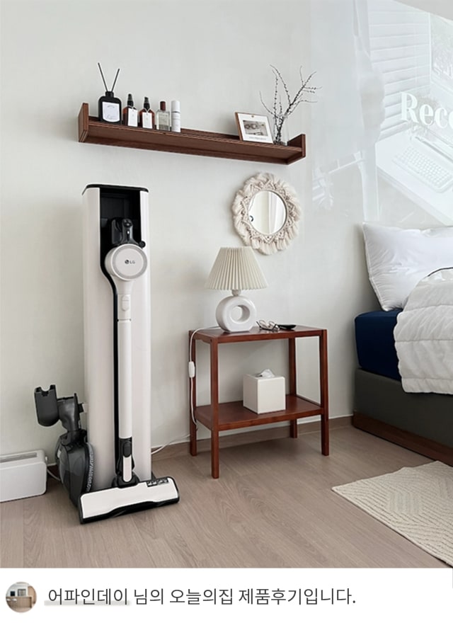 LG 코드제로 오브제컬렉션 A9S 무선청소기가 침실 벽 옆에 놓인 모습. 화이트톤 벽과 나무 선반, 아늑한 침구가 어우러진 공간에 청소기가 잘 배치되어 있으며, 하단에는 '어파인데이 님의 오늘의집 제품후기입니다.'라는 텍스트가 포함되어 있음.
