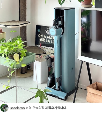 LG 코드제로 오브제컬렉션 A9S 스틱 청소기가 거치대에 놓여 있고 주변에 식물이 배치된 모습이며, 'soodaroo 님의 오늘의집 제품후기입니다.' 텍스트가 포함된 모습.